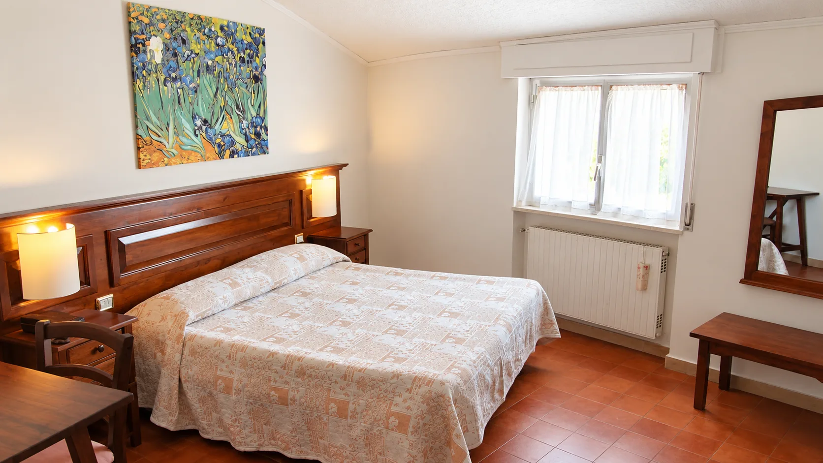 Camera doppia con letto matrimoniale, pavimento in cotto e finestra luminosa
